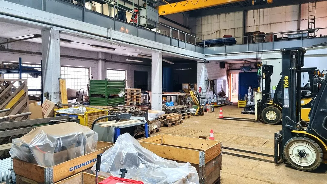 Lagerhalle mit Gitterboxen, Paletten und Gabelstapler während einer Betriebsauflösung